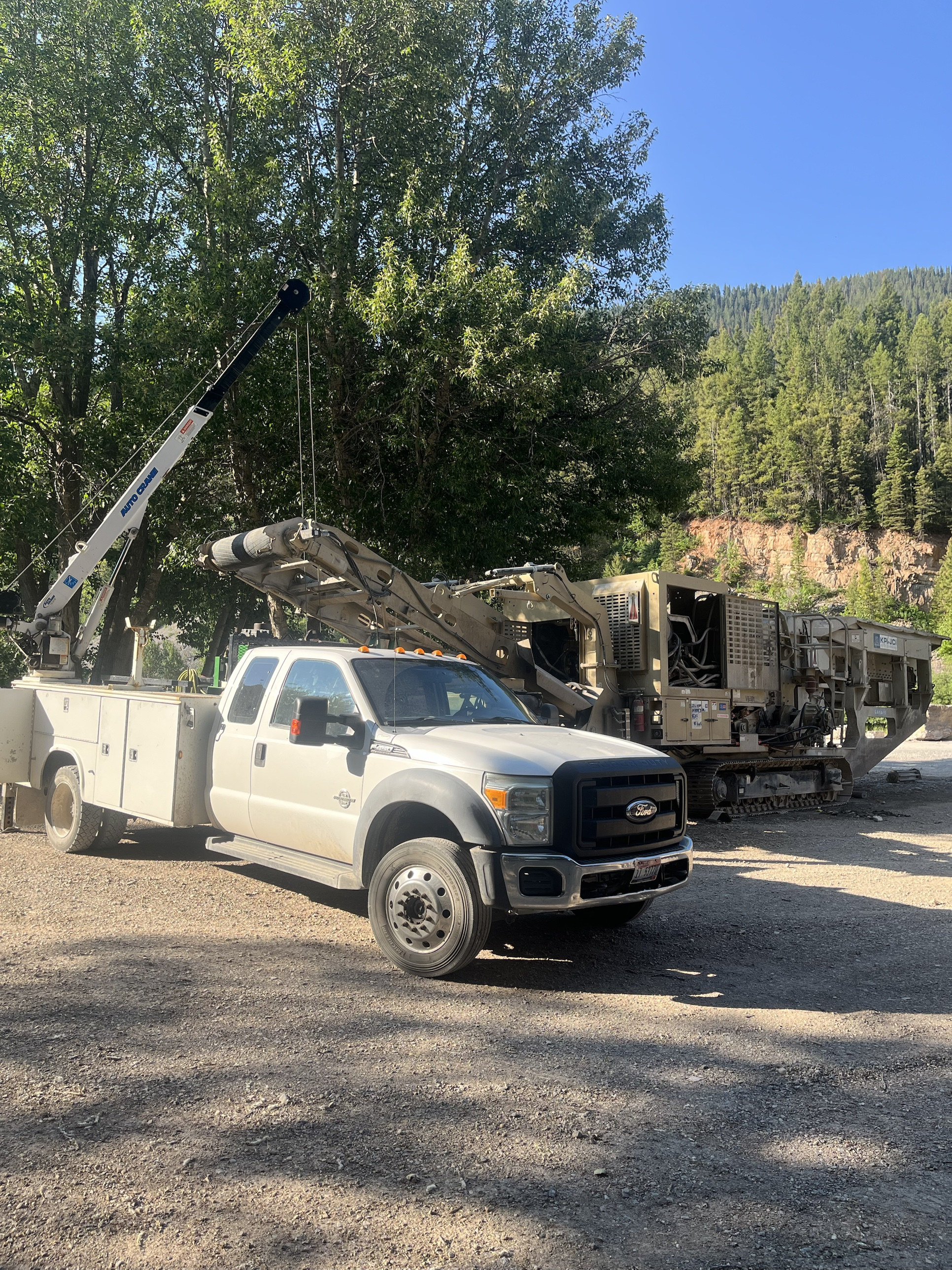 Mountainside Fleet service truck parked beside a tracked rock crusher in the mountains