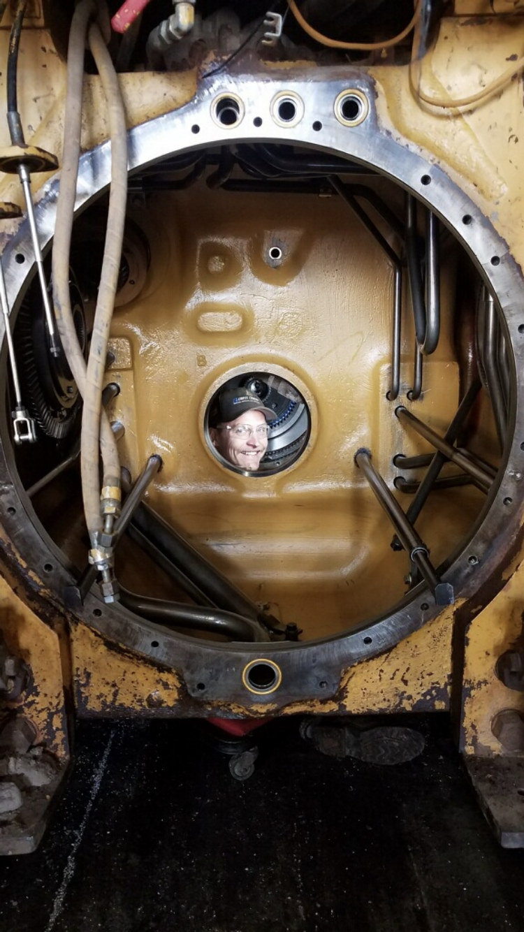 Mechanic peeking through a heavy equipment bellhousing