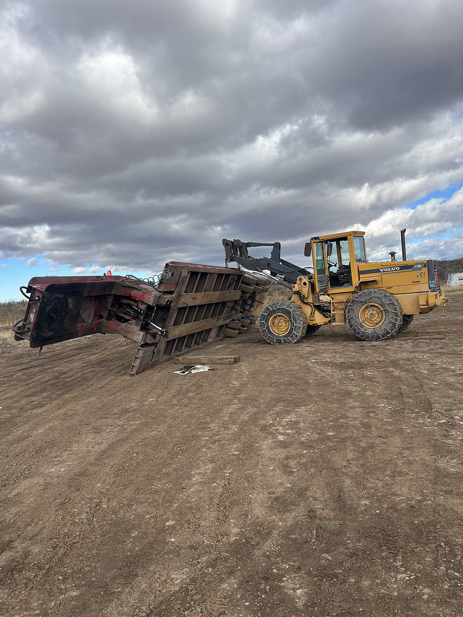Loader lifting a lowboy trailer for repair